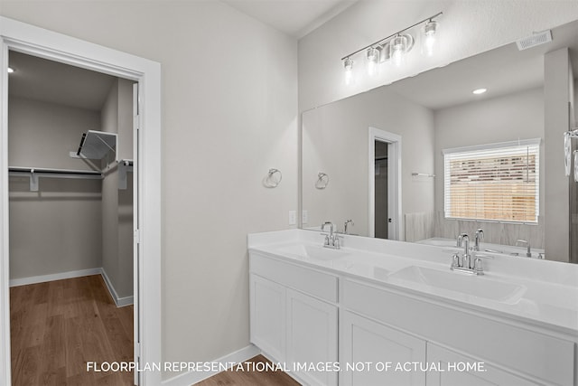 bathroom with hardwood / wood-style flooring, vanity, and a tub