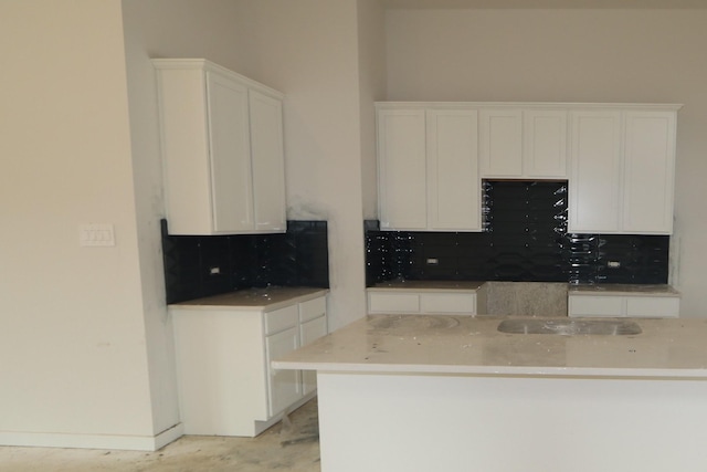 kitchen featuring backsplash, white cabinets, and baseboards