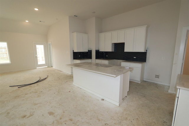 kitchen featuring a center island, white cabinetry, recessed lighting, decorative backsplash, and baseboards