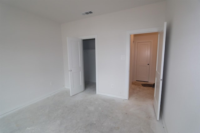 unfurnished bedroom with visible vents, a closet, baseboards, concrete flooring, and a spacious closet