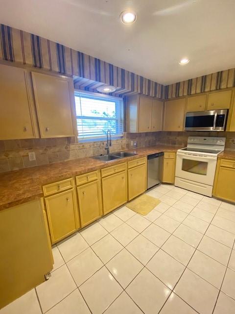 kitchen with backsplash, sink, light tile patterned floors, and stainless steel appliances