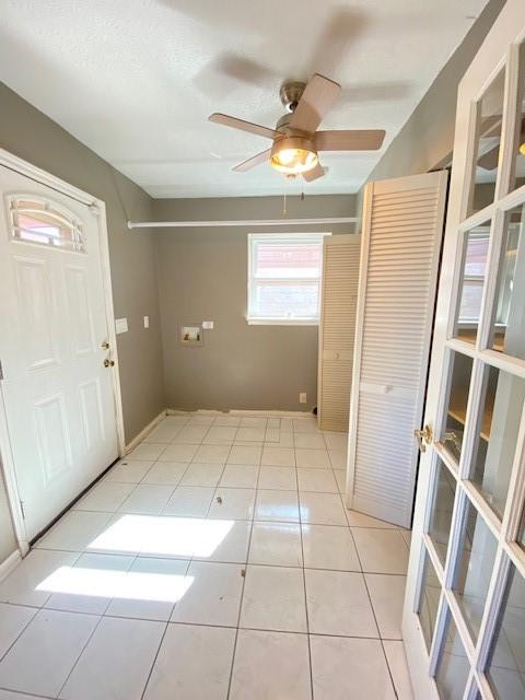 foyer entrance with ceiling fan and light tile patterned floors