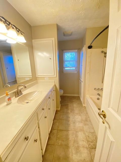 full bathroom featuring vanity, bathtub / shower combination, a textured ceiling, and toilet