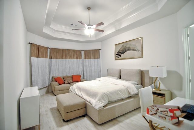 bedroom featuring light hardwood / wood-style flooring, a raised ceiling, ceiling fan, and ornamental molding