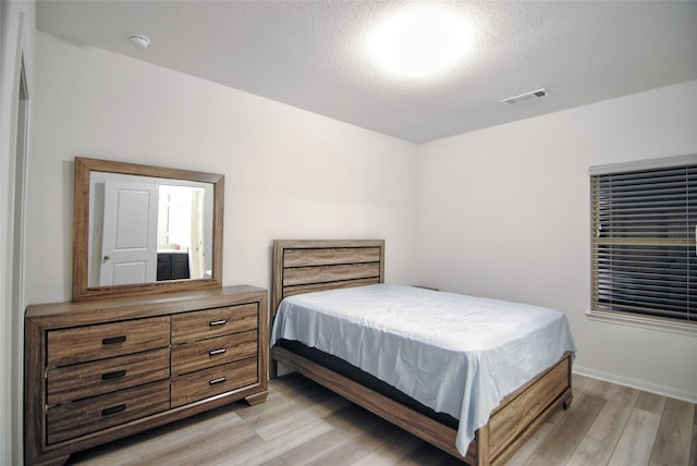 bedroom with light hardwood / wood-style floors and a textured ceiling