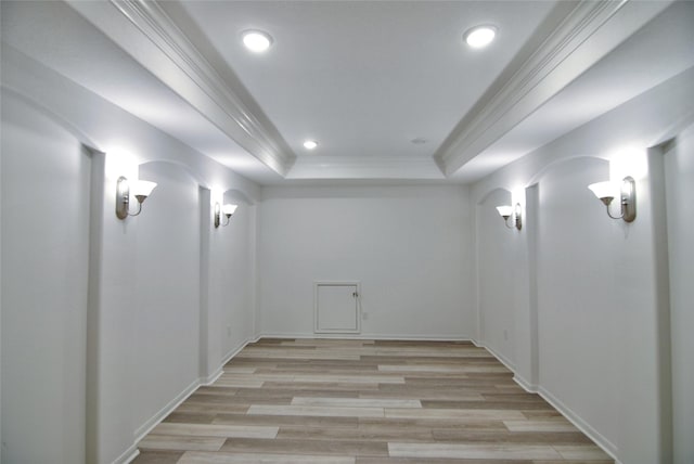 interior space featuring a raised ceiling, ornamental molding, and light wood-type flooring