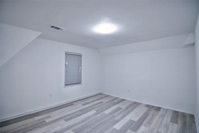 bonus room featuring vaulted ceiling, light hardwood / wood-style flooring, and a textured ceiling