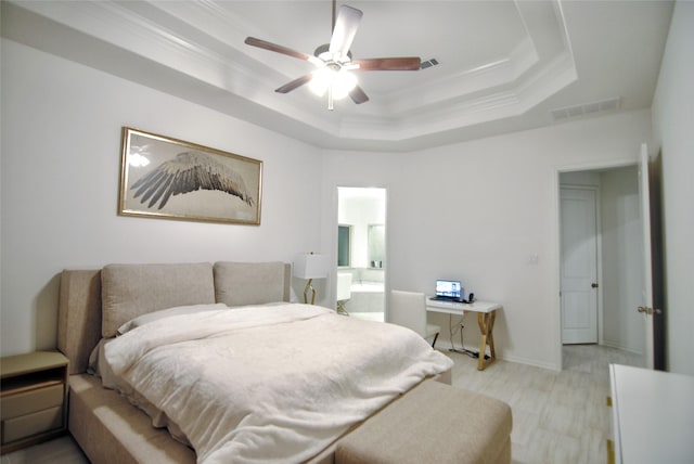 bedroom with a tray ceiling, ensuite bath, ceiling fan, and ornamental molding