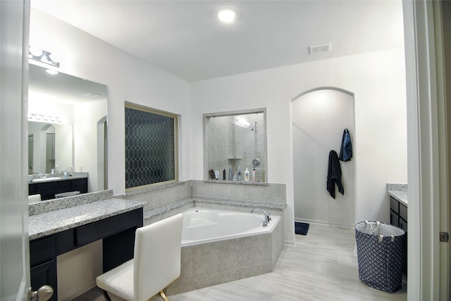 bathroom with vanity and tiled bath