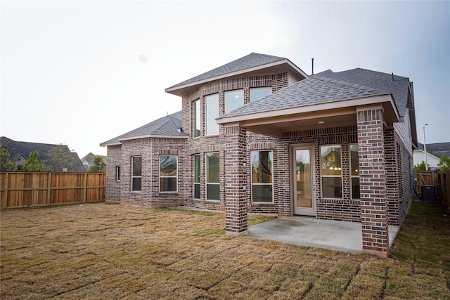 back of house featuring a lawn, a patio area, and central AC