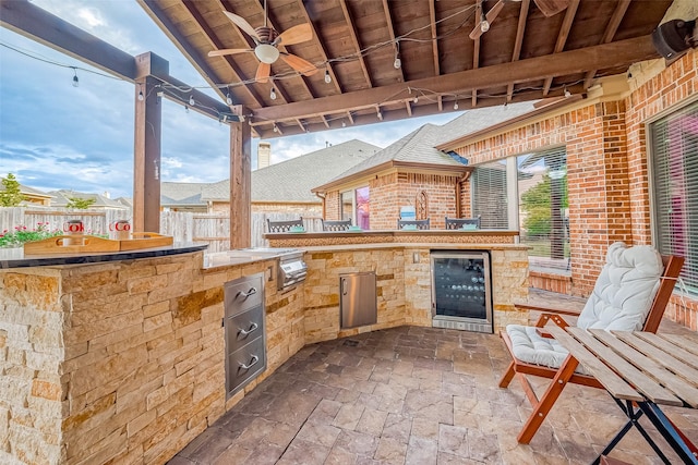 view of patio / terrace featuring exterior kitchen, beverage cooler, fence, and ceiling fan