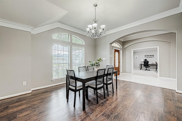 dining area with a notable chandelier, dark hardwood / wood-style flooring, ornamental molding, and vaulted ceiling