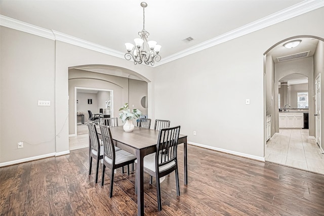 dining room featuring wood-type flooring, ornamental molding, and a chandelier