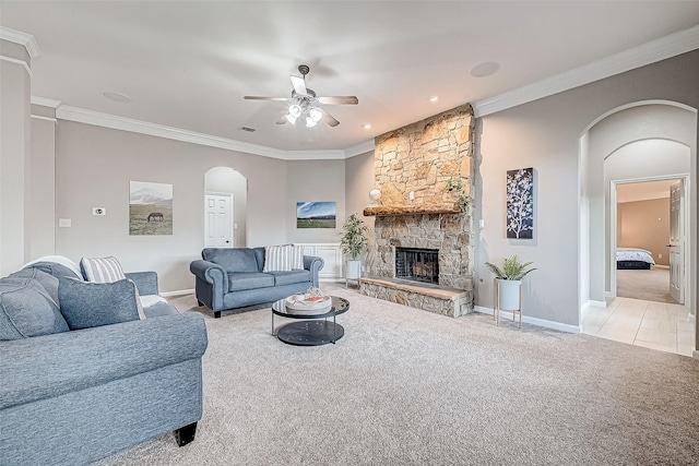 carpeted living room with ceiling fan, crown molding, and a fireplace