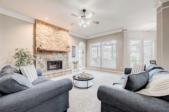 carpeted living room with a stone fireplace, ceiling fan, and ornamental molding