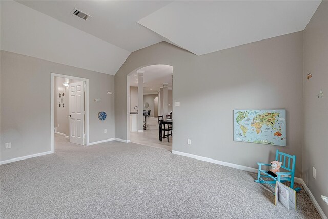 carpeted spare room featuring vaulted ceiling