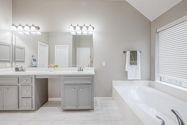 bathroom featuring a bathtub, vanity, vaulted ceiling, and tile patterned flooring