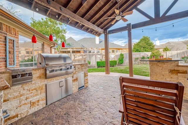 view of patio with ceiling fan, area for grilling, and exterior kitchen