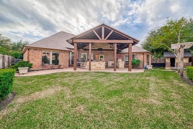 rear view of house with ceiling fan, a yard, and a patio