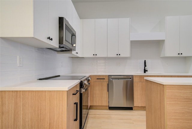 kitchen featuring backsplash, sink, light hardwood / wood-style floors, white cabinetry, and stainless steel appliances