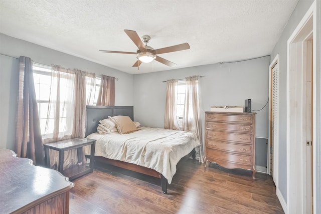 bedroom with a closet, ceiling fan, dark hardwood / wood-style flooring, and a textured ceiling