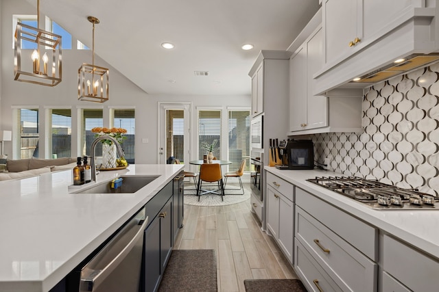 kitchen with custom exhaust hood, backsplash, sink, hanging light fixtures, and stainless steel appliances