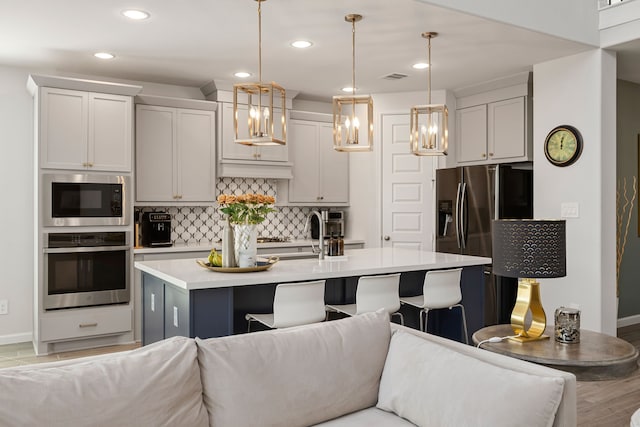 kitchen featuring a kitchen bar, built in microwave, stainless steel oven, and decorative light fixtures