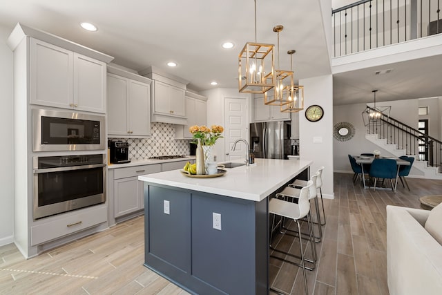 kitchen with sink, hanging light fixtures, stainless steel appliances, a breakfast bar, and a center island with sink