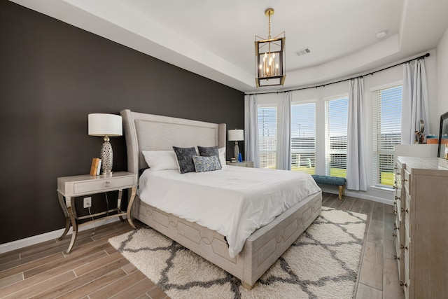 bedroom featuring a raised ceiling and an inviting chandelier