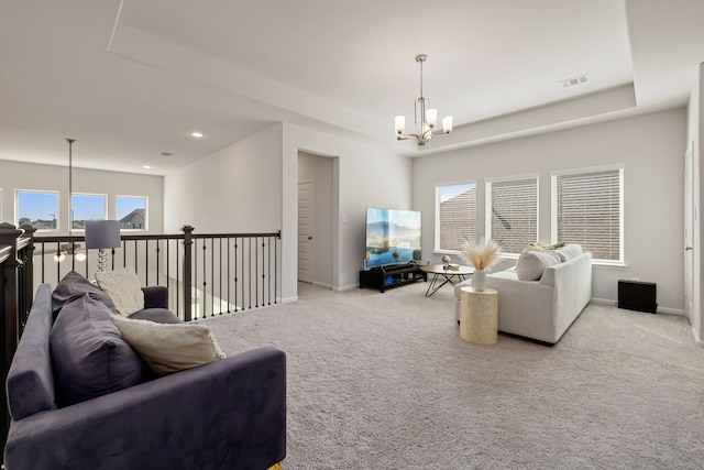 living room with a raised ceiling, light carpet, and a notable chandelier