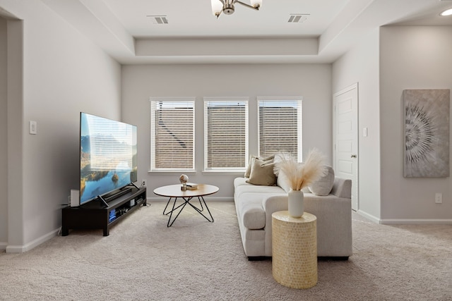 carpeted living room featuring a chandelier and a tray ceiling