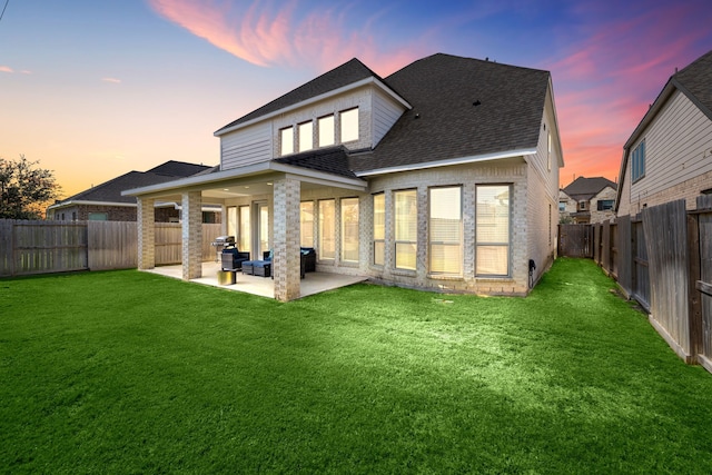 back house at dusk with outdoor lounge area, a yard, and a patio