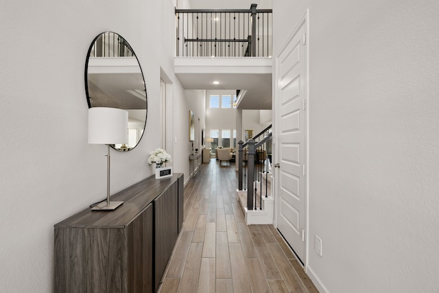 interior space with light wood-type flooring and a towering ceiling