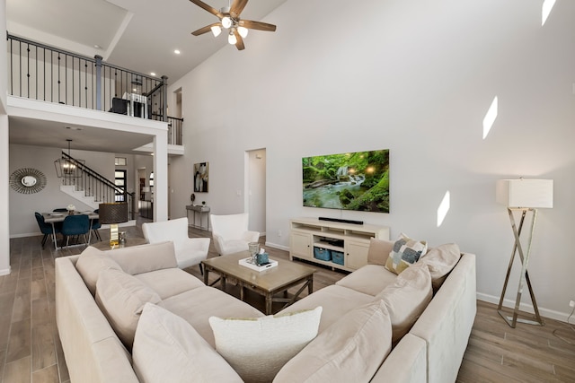 living room featuring a high ceiling, light hardwood / wood-style floors, and ceiling fan