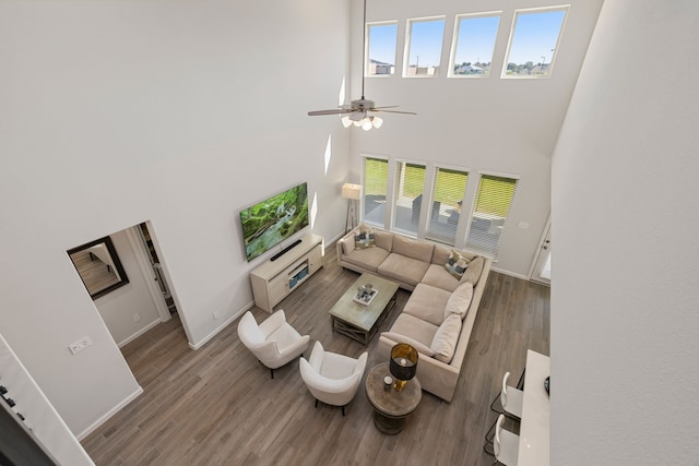 living room featuring ceiling fan, wood-type flooring, and a high ceiling