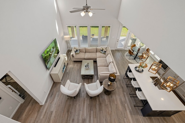 living room featuring ceiling fan with notable chandelier, hardwood / wood-style floors, and a towering ceiling