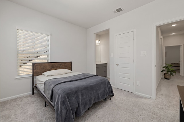 bedroom featuring light carpet and ensuite bathroom