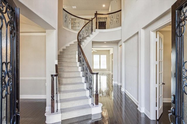 entryway featuring a towering ceiling, crown molding, and dark wood-type flooring