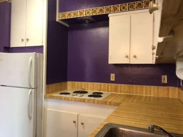 kitchen with white cabinetry, white appliances, and sink