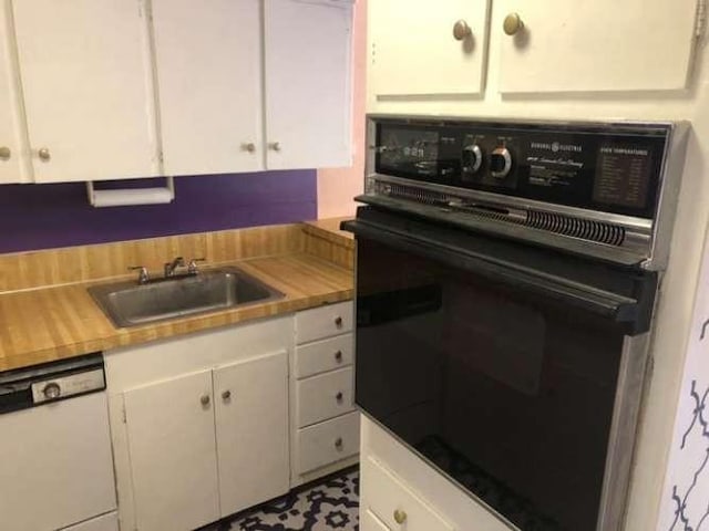 kitchen with white cabinets, dishwasher, sink, and black oven