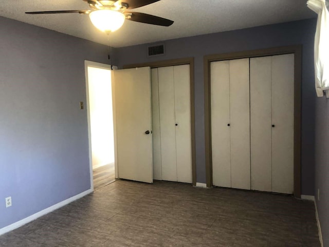 unfurnished bedroom with multiple closets and ceiling fan