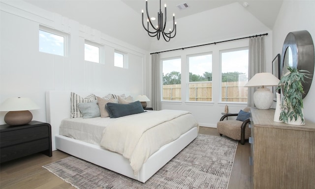 bedroom featuring wood-type flooring, vaulted ceiling, and a notable chandelier