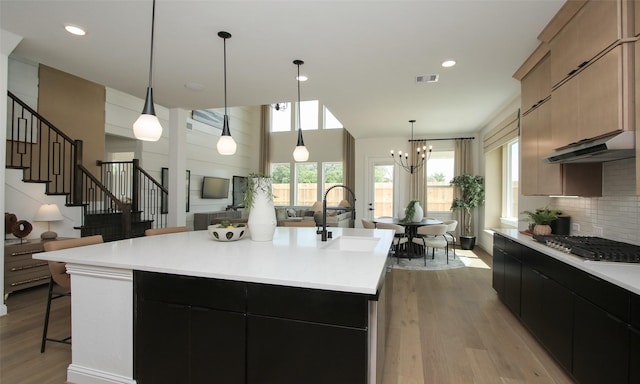 kitchen featuring sink, light brown cabinets, an island with sink, light hardwood / wood-style floors, and stainless steel gas stovetop