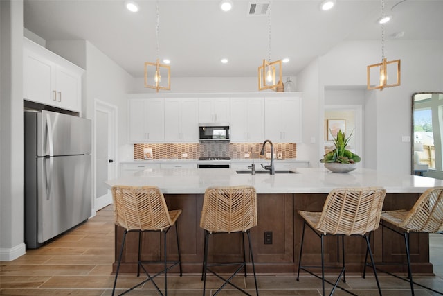 kitchen with stainless steel appliances, a kitchen island with sink, and sink