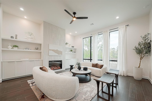 living room with ceiling fan, dark hardwood / wood-style flooring, a fireplace, and built in shelves