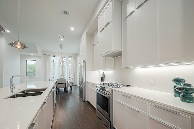 kitchen featuring pendant lighting, sink, high end appliances, dark wood-type flooring, and white cabinets