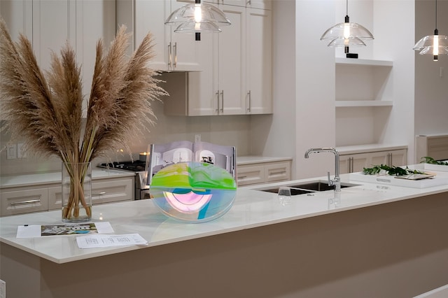 kitchen featuring pendant lighting, kitchen peninsula, sink, light stone countertops, and white cabinets