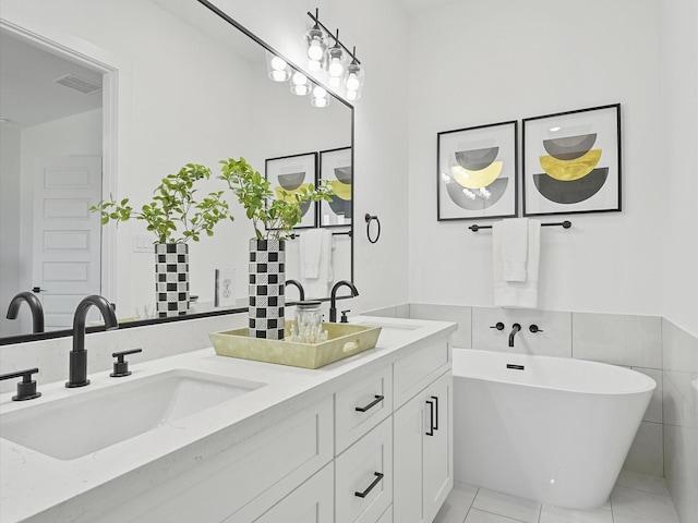 bathroom with a washtub, vanity, tile walls, and tile patterned flooring