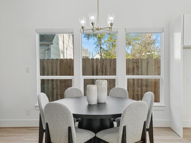 dining space with a wealth of natural light, light wood-type flooring, and a notable chandelier