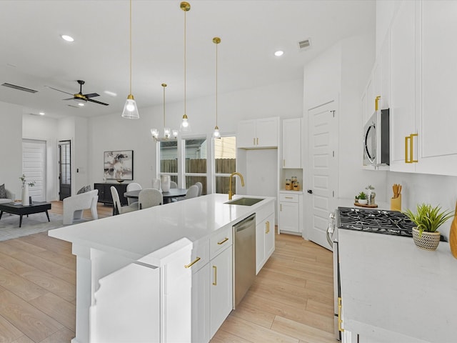 kitchen with appliances with stainless steel finishes, white cabinetry, and an island with sink